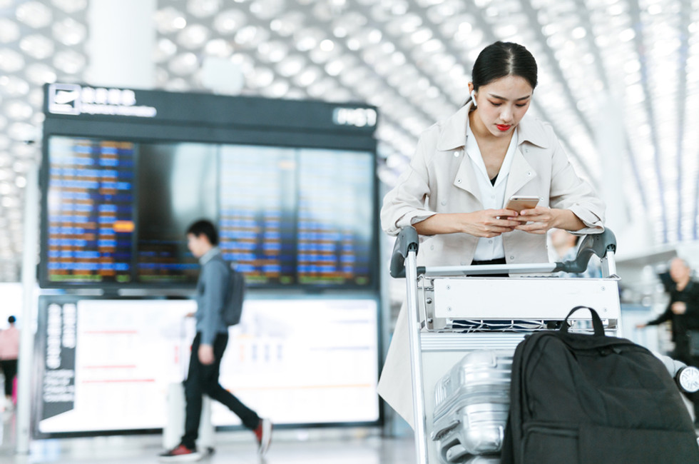 Vrouw die out-of-office goedkeuringen maakt voor personeelsuitgaven en fondsaanvragen indient op de luchthaven met Payhawk